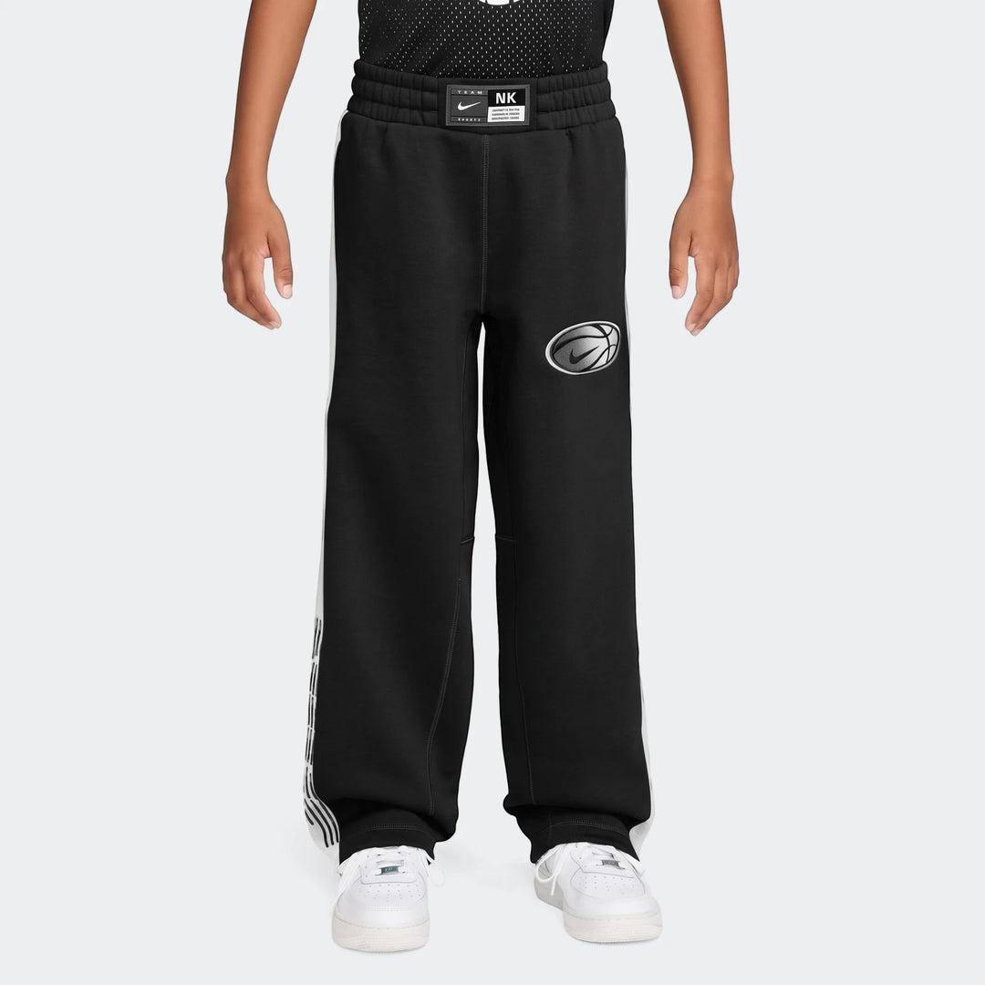 Nike Big Kids' black basketball pants with white side stripes and a silver basketball logo, worn by a child.