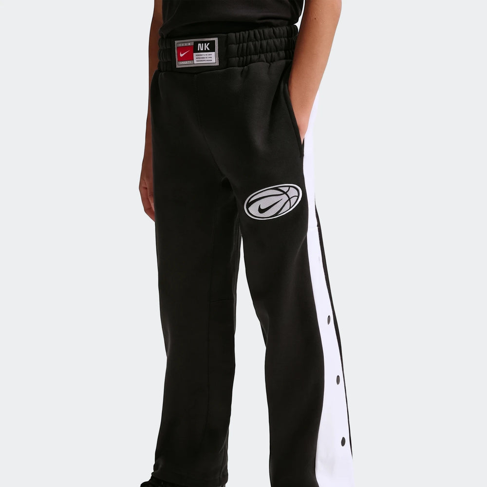 Nike Big Kids' black basketball pants with white side stripes and snap buttons, featuring an embroidered logo, worn by a