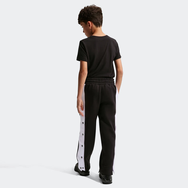 Nike Big Kids' black and white snap-button basketball pants, worn by a boy from the back.