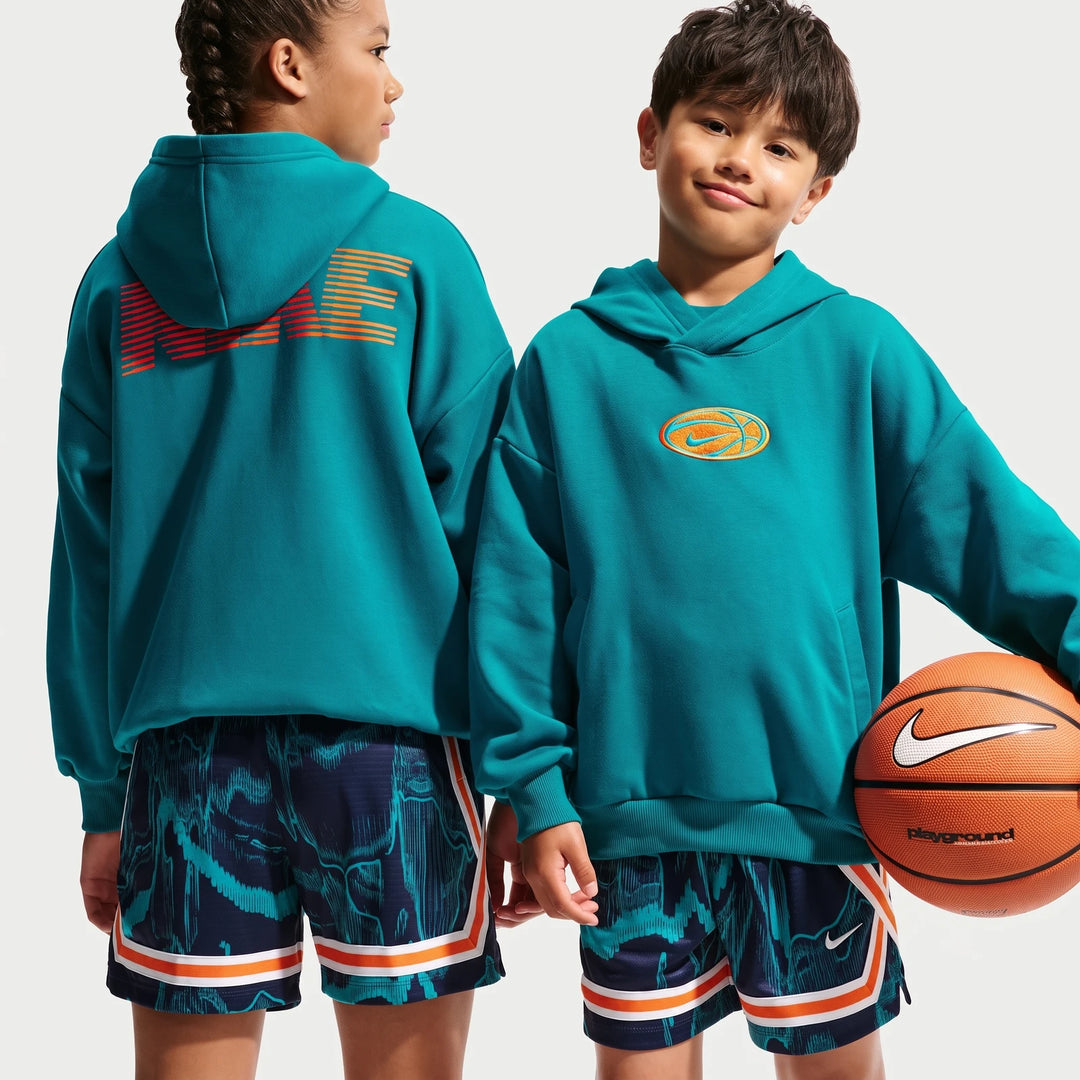 Two kids model teal Nike Big Kids' Dri-Fit Basketball Hoodies with patterned shorts, one holding a Nike basketball.