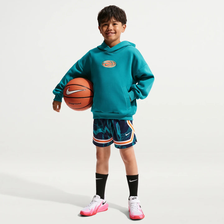Young boy wearing a teal Nike Big Kids' Dri-Fit Basketball Hoodie and matching shorts, holding a basketball, smiling.