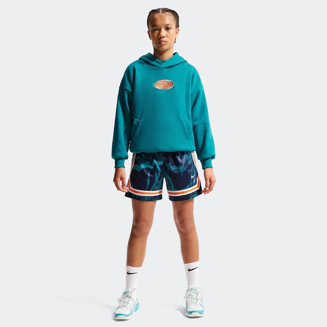 Young person wearing a teal Nike Big Kids' Dri-Fit Basketball Hoodie, dark blue basketball shorts, and white sneakers,