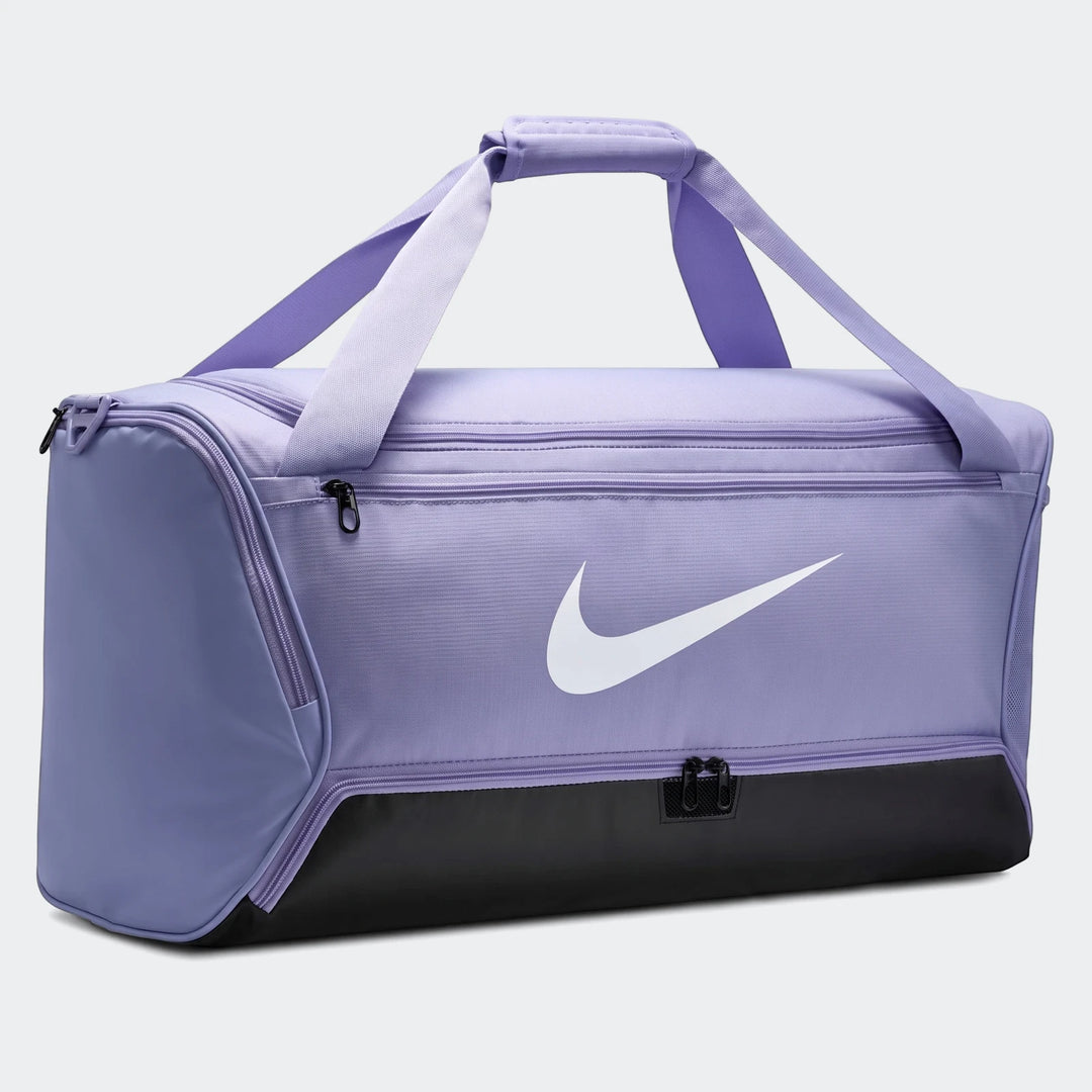 Purple and black Nike Brasila M 9.5 duffel bag for sports and travel, featuring a prominent white swoosh logo on the side.