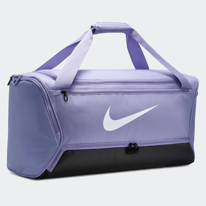 Purple and black Nike Brasila M 9.5 duffel bag for sports and travel, featuring a prominent white swoosh logo on the side.