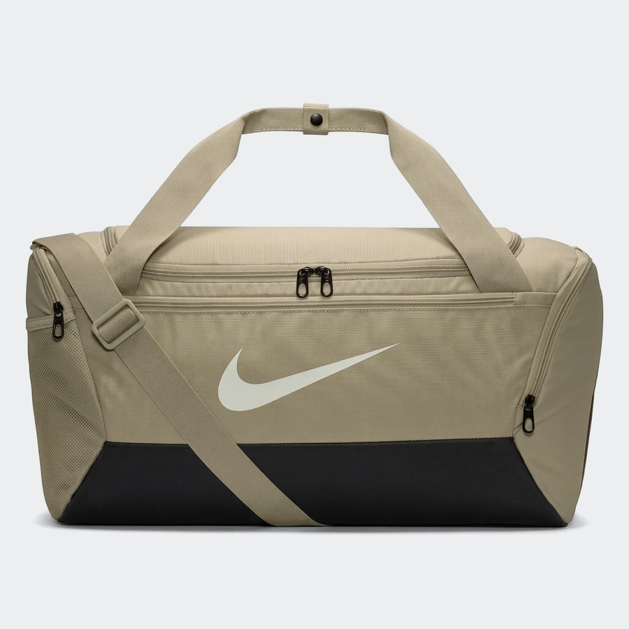A brown Nike Brasilia 9.5 small duffel bag with black bottom panel, white swoosh logo, and shoulder strap, displayed on a