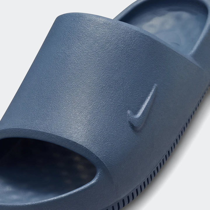 Close-up view of a single blue Nike Calm 2.0 Men's Slide, featuring a textured surface and an embossed swoosh logo.