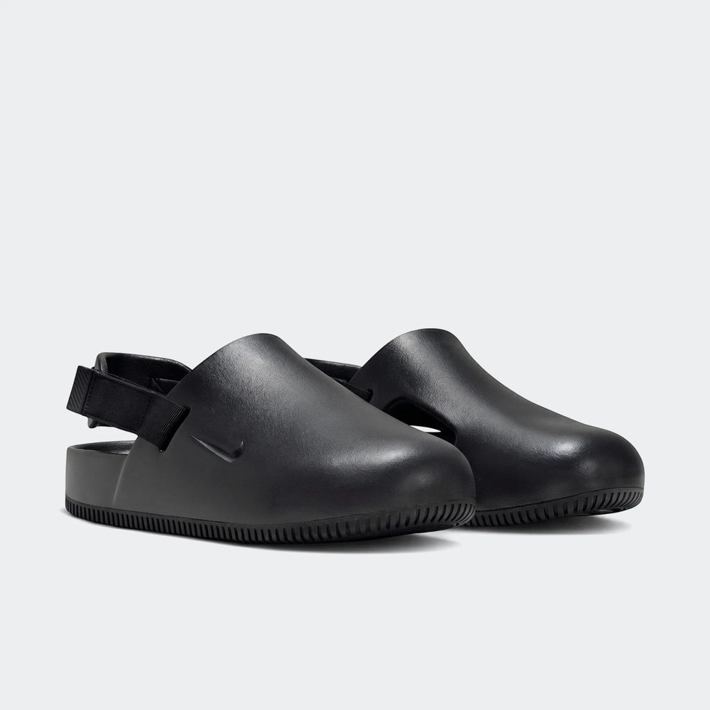 Pair of Nike Calm black men's mules, featuring a smooth, slip-on design with an adjustable heel strap, presented in a side