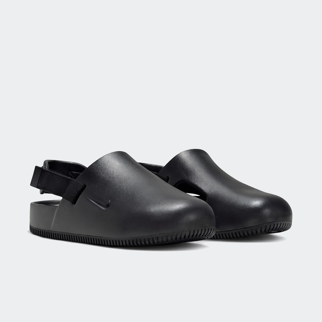 Pair of Nike Calm black men's mules, featuring a smooth, slip-on design with an adjustable heel strap, presented in a side
