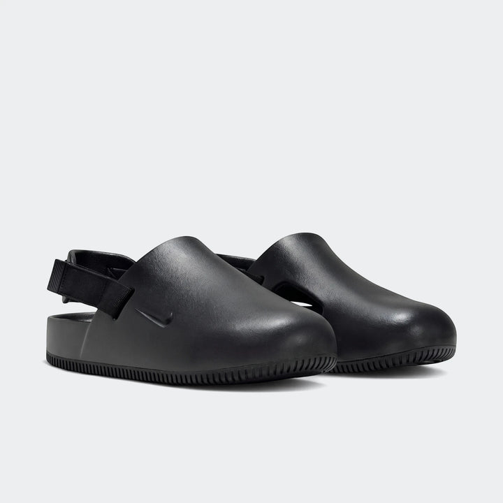 Pair of Nike Calm black men's mules, featuring a smooth, slip-on design with an adjustable heel strap, presented in a side