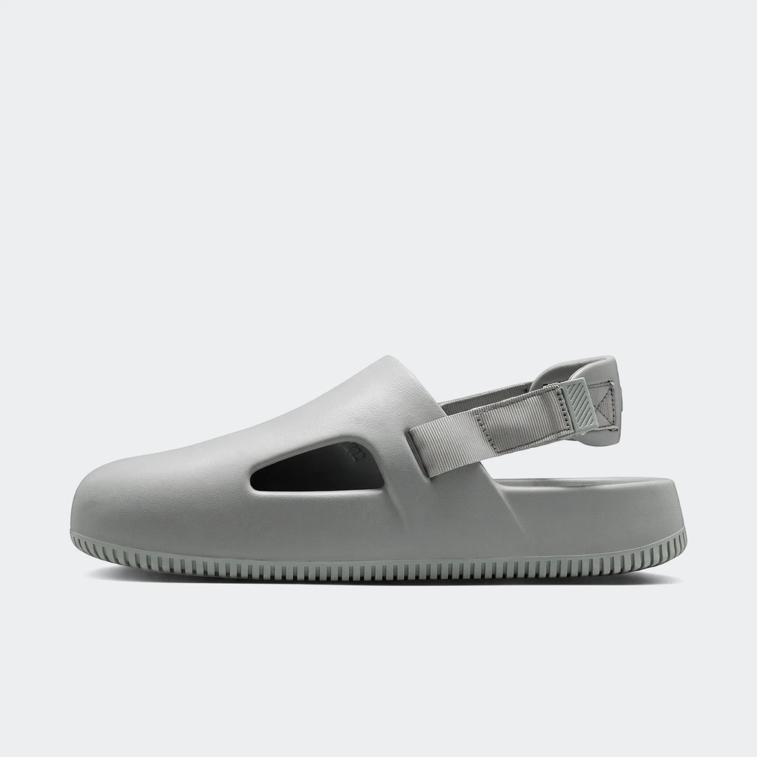 Light gray Nike Calm Men's Mules, shown in a side profile view, highlighting the molded design and adjustable heel strap.