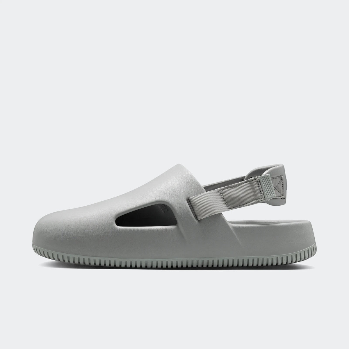 Light gray Nike Calm Men's Mules, shown in a side profile view, highlighting the molded design and adjustable heel strap.