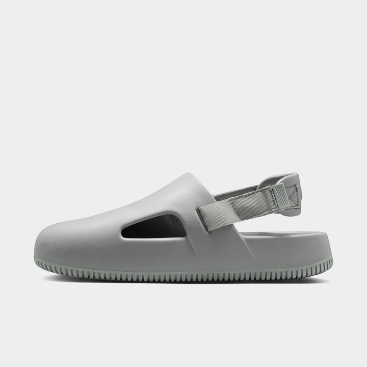 Light gray Nike Calm Men's Mules, shown in a side profile view, highlighting the molded design and adjustable heel strap.