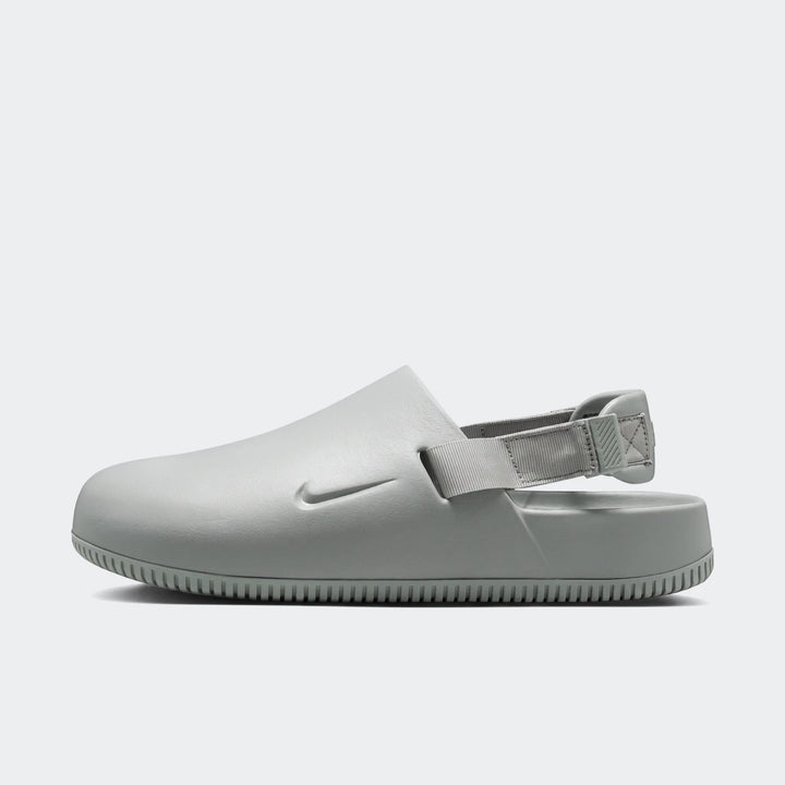 Nike Calm Men's Mules in light grey, shown in a side profile view, highlighting the ergonomic design and textured sole.