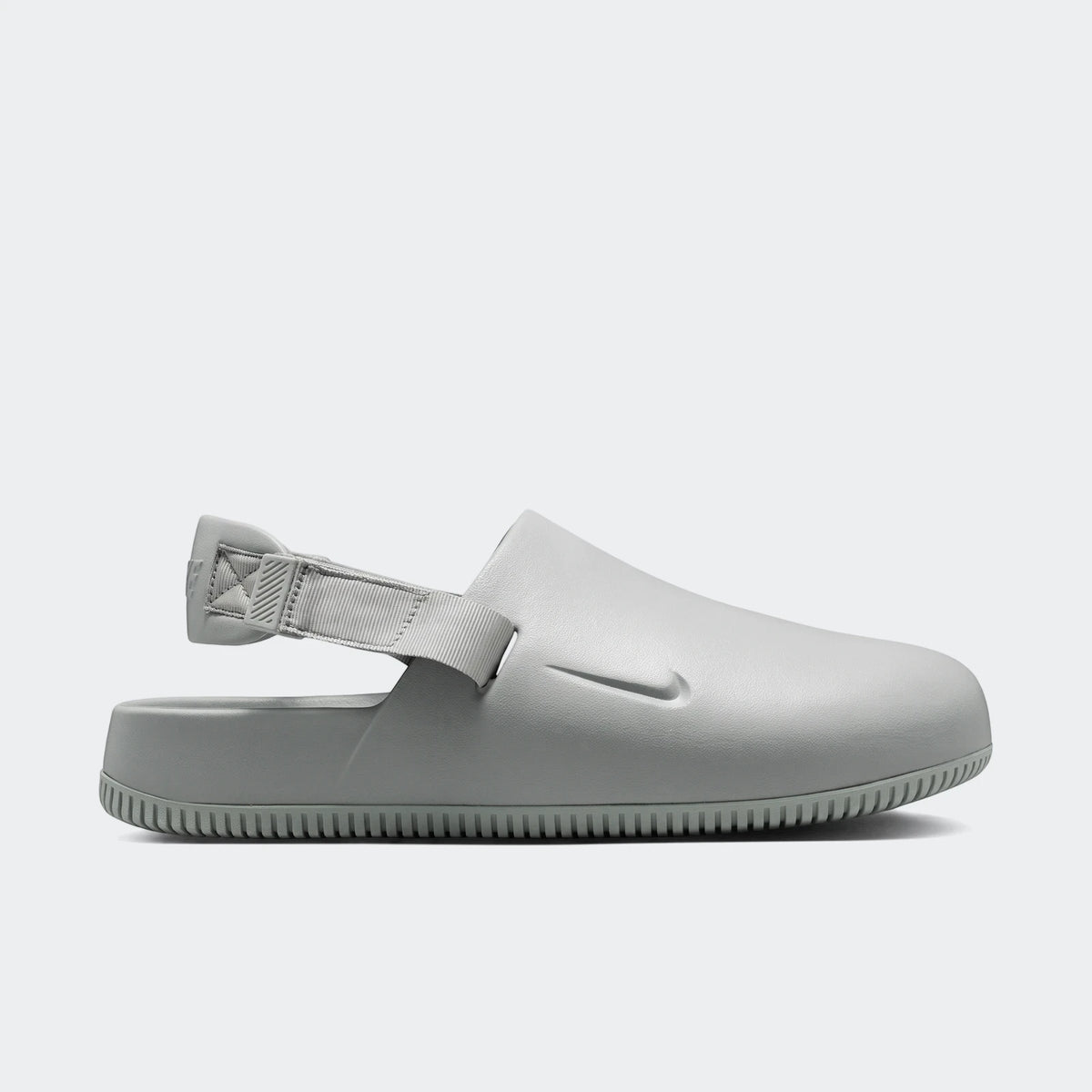 Light grey Nike Calm Men's Mules, shown in a side profile, featuring a smooth slip-on design with an adjustable heel strap.