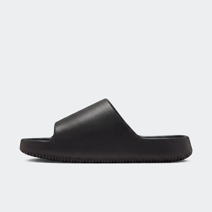 A single Nike Calm Slide 2.0 in black, featuring a smooth, contoured upper and a ribbed sole, presented from a side angle on