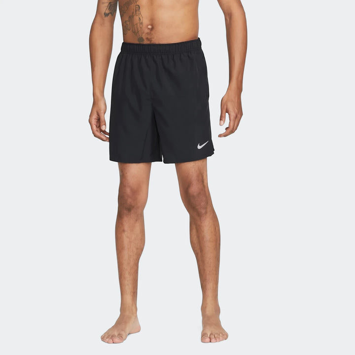 Black Nike Challenger Men's Dri-Fit unlined running shorts on a male model, front view, standing barefoot.