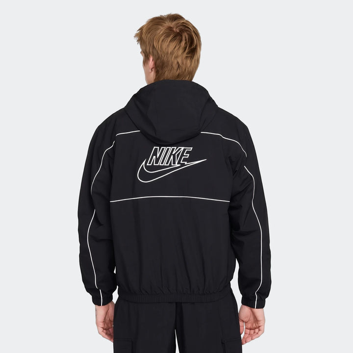 Back view of a man wearing a black Nike Club hooded jacket with a large white Nike logo and white piping details.