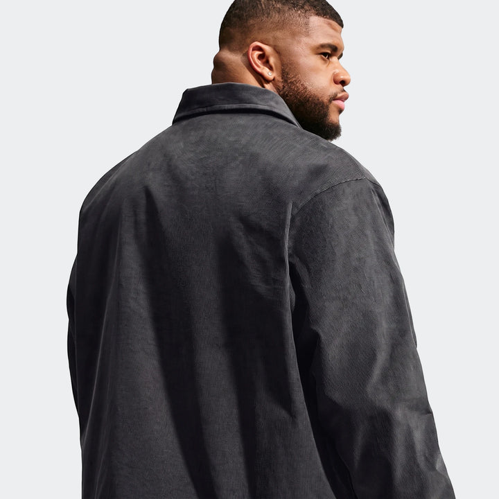 Back view of a man wearing a dark grey Nike Club Men's Corduroy Coaches Jacket, showcasing the ribbed texture and collar.