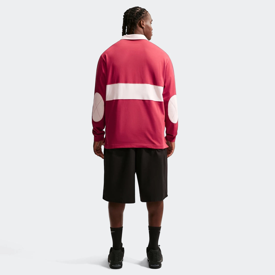 Nike Club Men's Long-Sleeve Rugby Top in red with a white stripe and elbow patches, styled with black shorts, viewed from