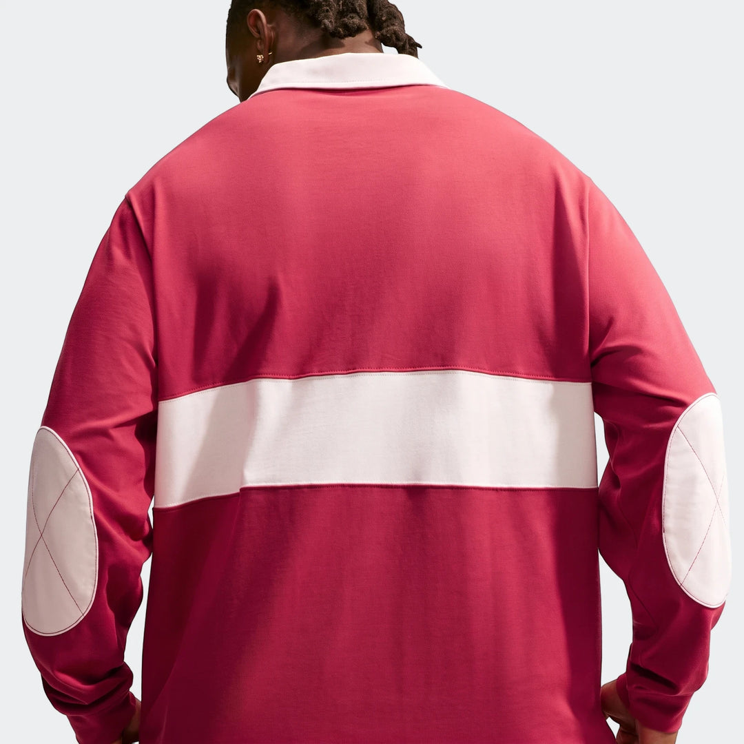 Back view of a man wearing a red and white Nike Club Men's Long-Sleeve Rugby Top, featuring elbow patches.