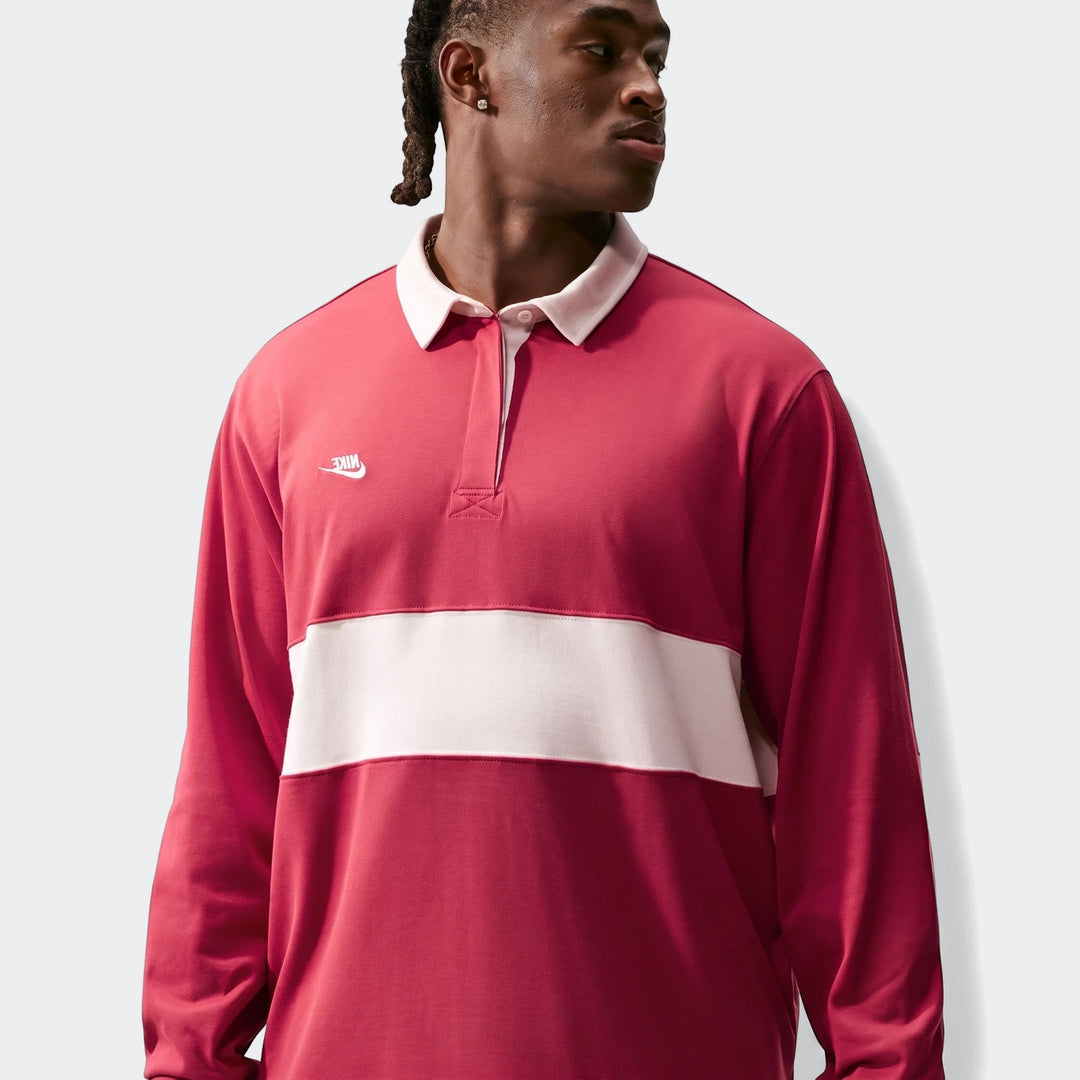 Nike Club Men's Long-Sleeve Rugby Top in red with a white chest stripe, worn by a male model looking right.