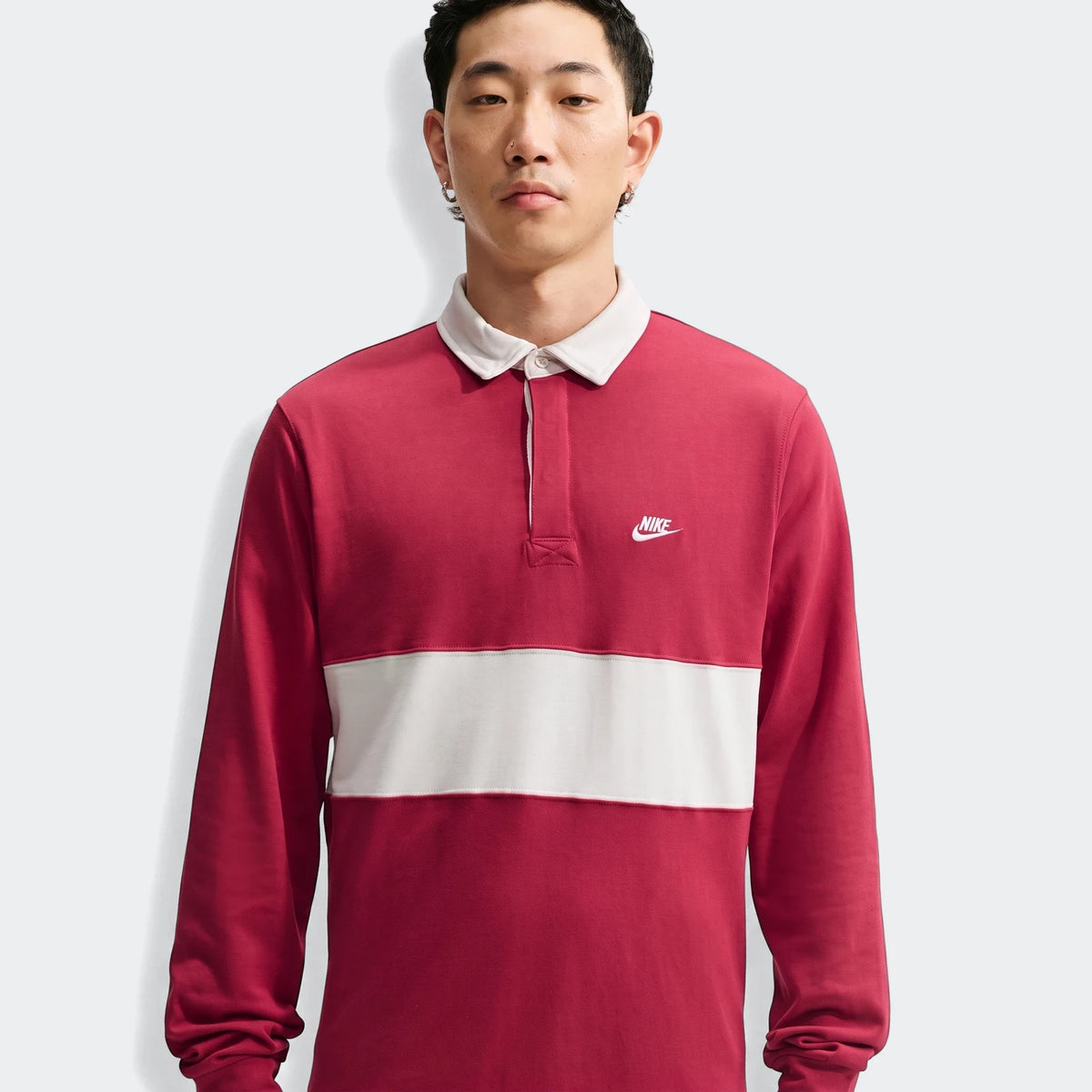 Nike Club Men's Long-Sleeve Rugby Top in red with a white horizontal stripe, worn by a male model.