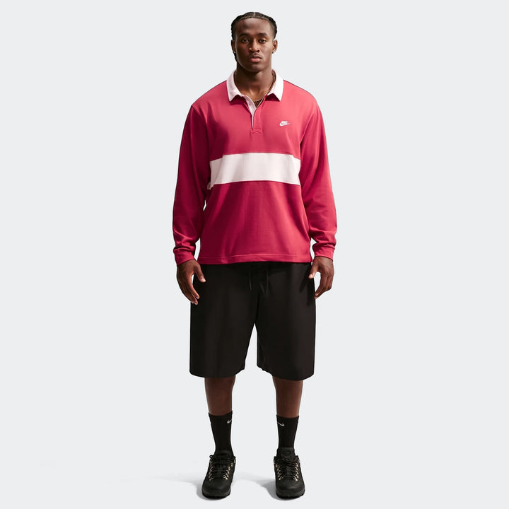 Male model wearing a red and white striped Nike Club Men's Long-Sleeve Rugby Top with black shorts.