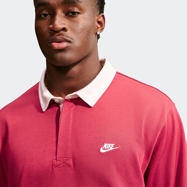 Close-up of a man wearing a red Nike Club Men's Long-Sleeve Rugby Top with a white collar and white Nike logo on the chest.