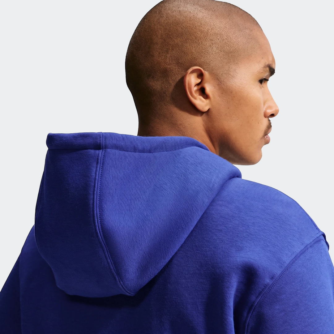 Nike Club Men's Pullover Fleece Hoodie in blue, shown on a model from an over-the-shoulder back view, highlighting the