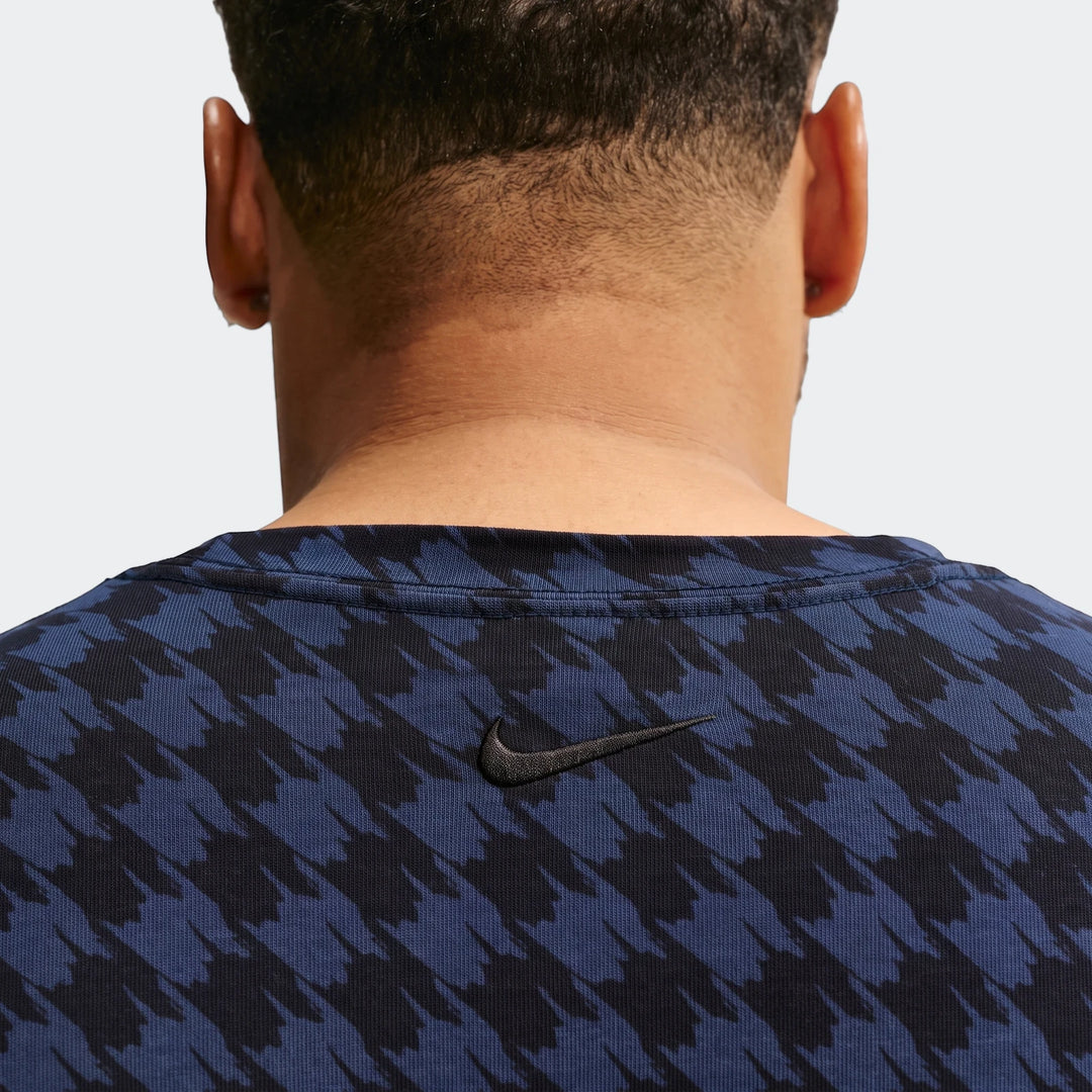 Back view of a person wearing a Nike Club Rules T-Shirt in blue and black houndstooth pattern.