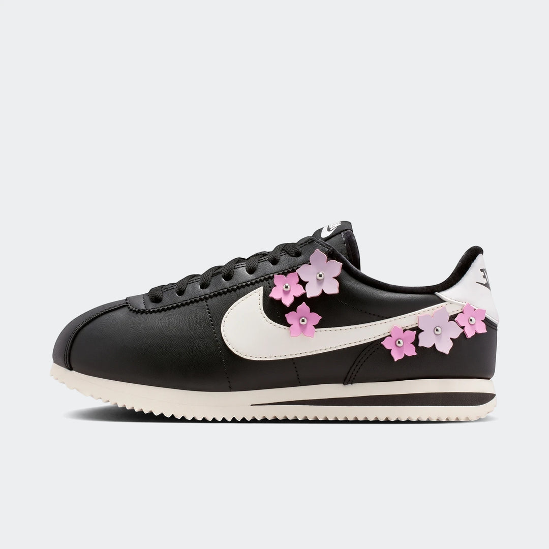 Black Nike Cortez Leather Women's Shoes with pink cherry blossom flower embellishments and a white swoosh, shown in a side