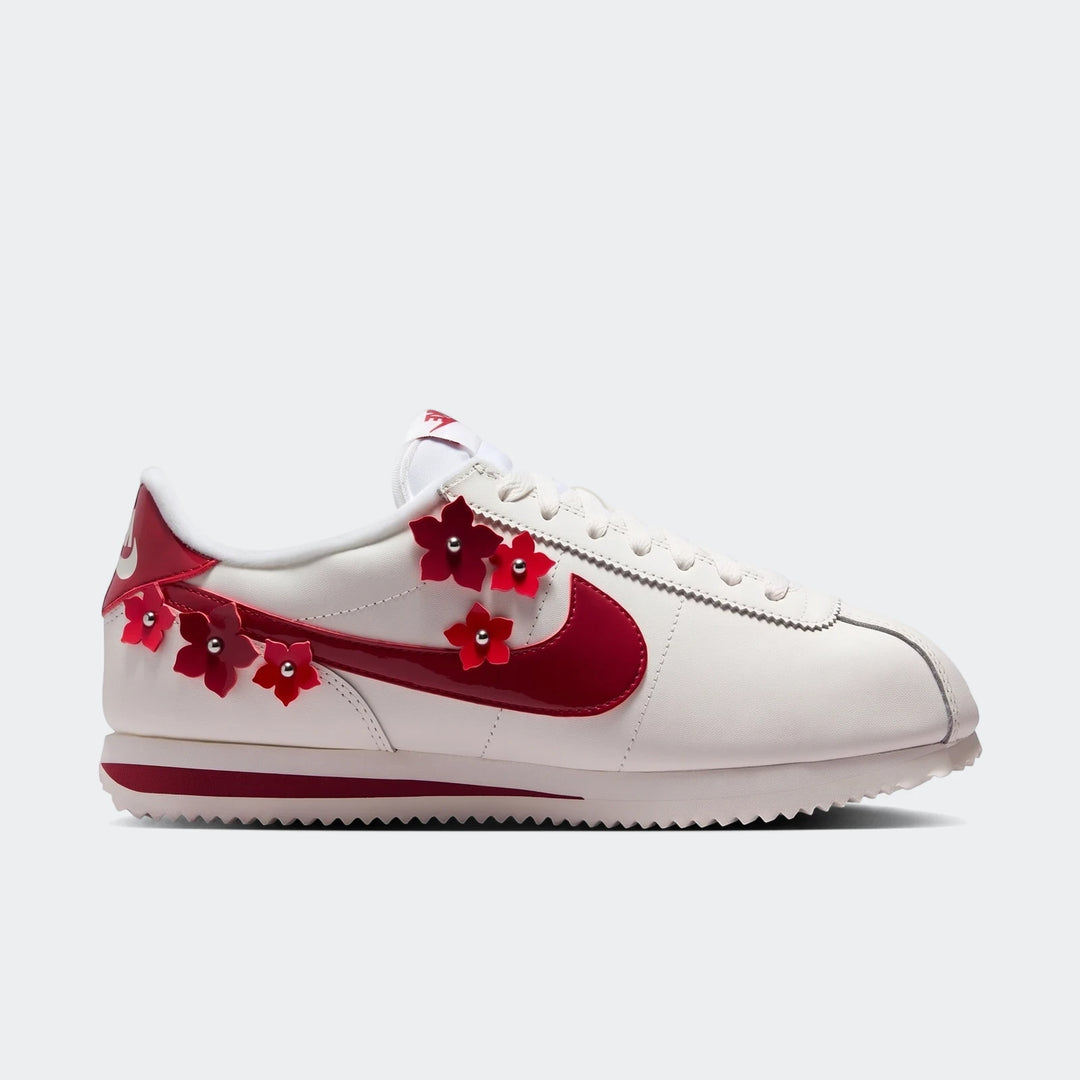 White Nike Cortez Leather Women's Shoes with a prominent red swoosh and delicate red floral appliqués, captured in a side
