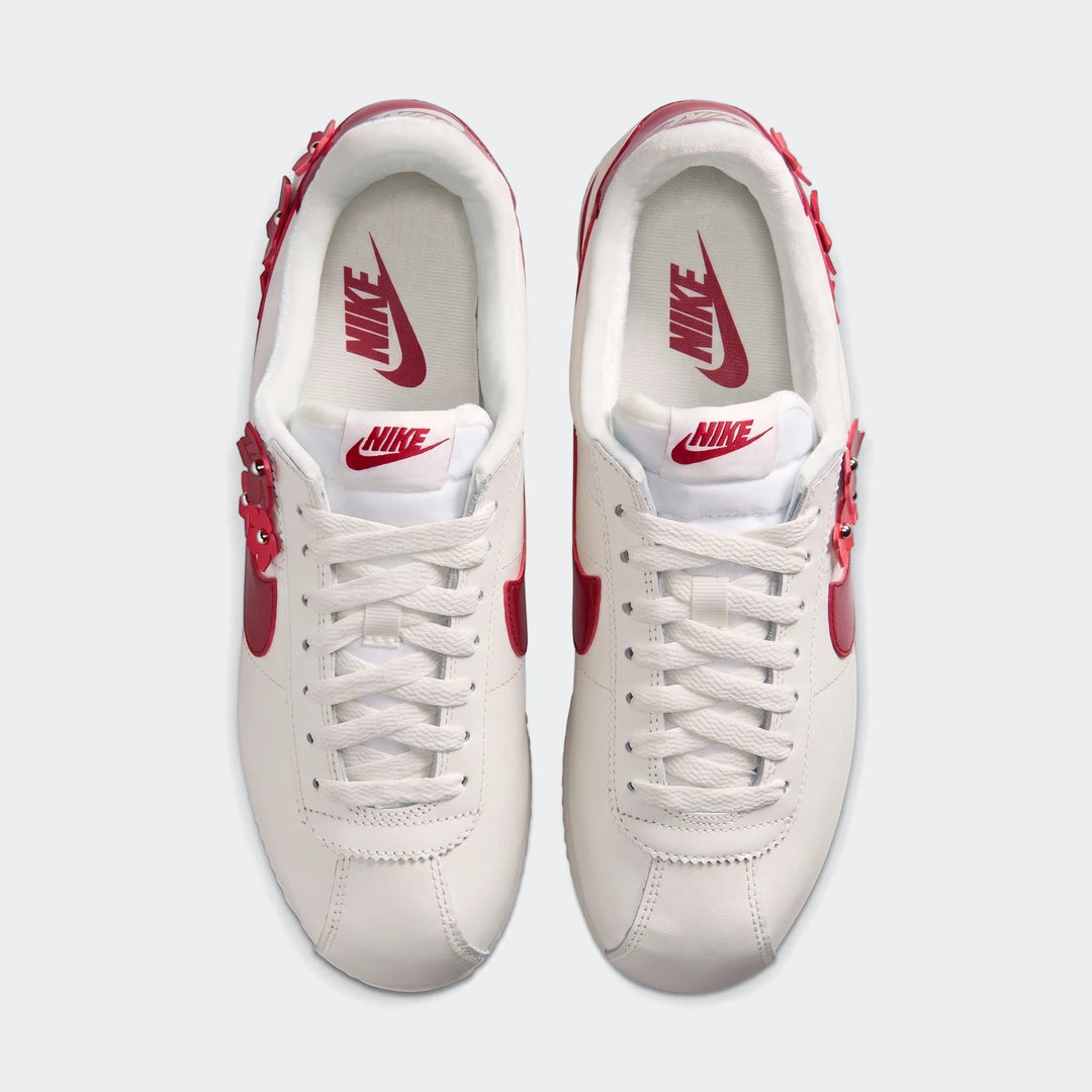 Top-down view of white Nike Cortez Leather Women's Shoes with red details and floral embellishments.