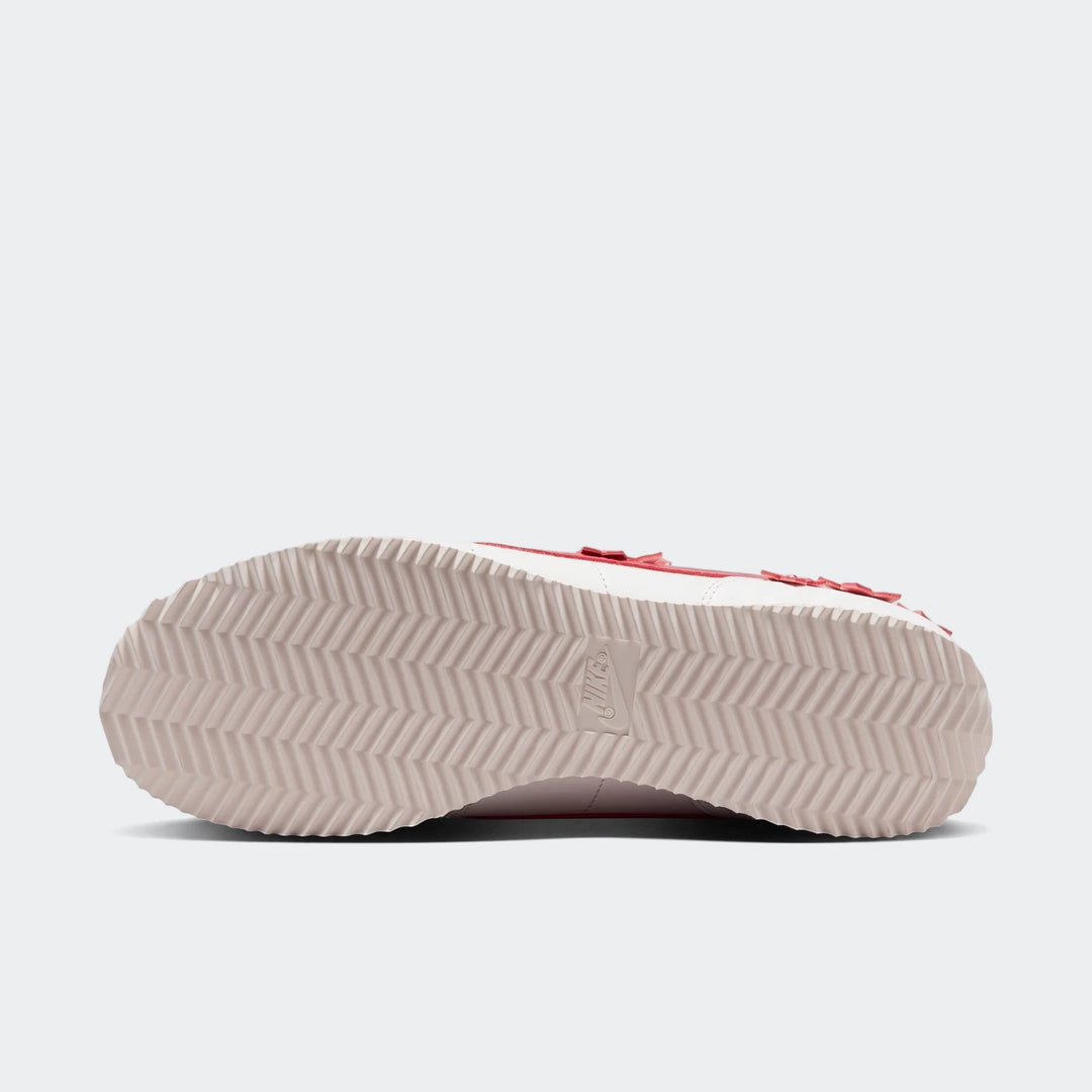 Bottom view of a white and red Nike Cortez Women's Leather shoe, showcasing the durable beige sole with herringbone tread