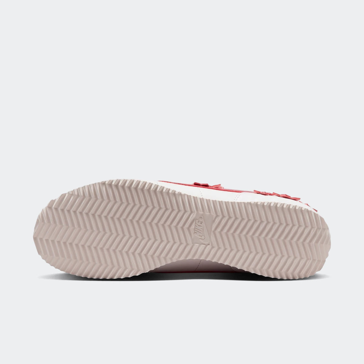 Bottom view of a white and red Nike Cortez Women's Leather shoe, showcasing the durable beige sole with herringbone tread