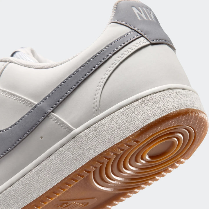 Angled close-up of the back-right side of a white and grey Nike Court Vision Low men's shoe with a gum sole, visible sole