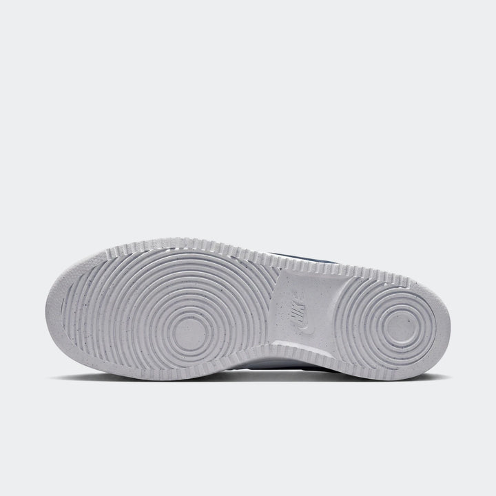 Bottom view of white Nike Court Vision Low men's shoes, showcasing the durable rubber outsole with speckled texture and
