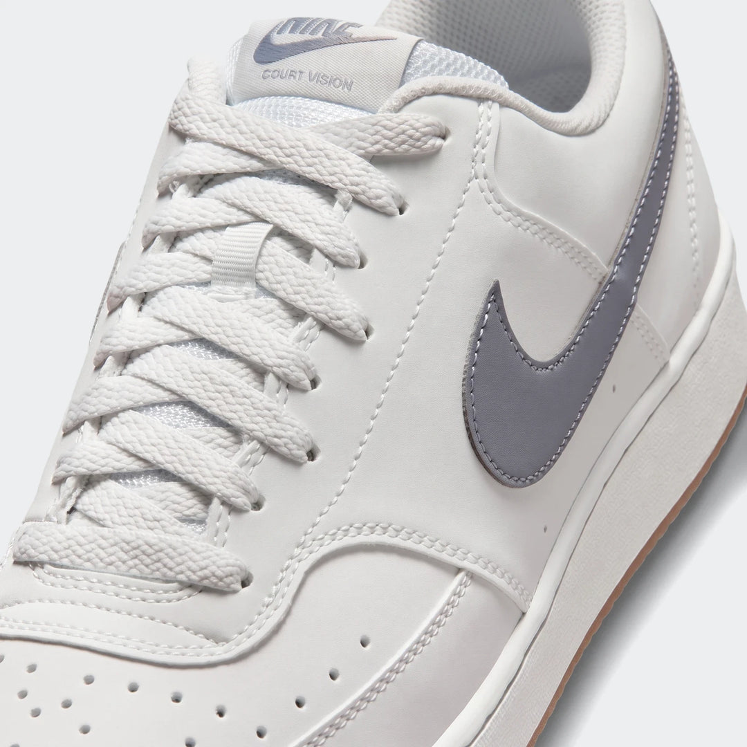 Close-up of a white Nike Court Vision Low men's athletic shoe with a grey swoosh and white laces.