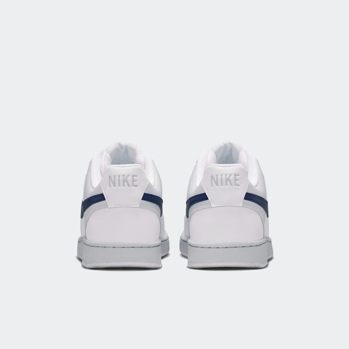 Rear view of two white Nike Court Vision Low men's shoes with navy blue accents and grey soles, displayed on a clean