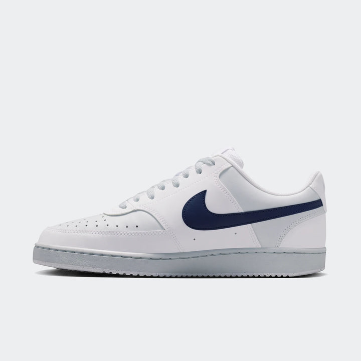 White Nike Court Vision Low Men's Shoes with a navy blue swoosh and grey sole, viewed from the side.
