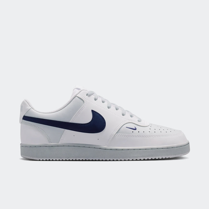 White Nike Court Vision Low Men's Shoes with a navy blue swoosh and light gray sole, shown in a side profile.