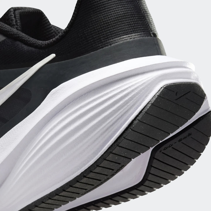 Close-up of a men's Nike Downshifter 14 road running shoe in black and white, showing the heel and sole.