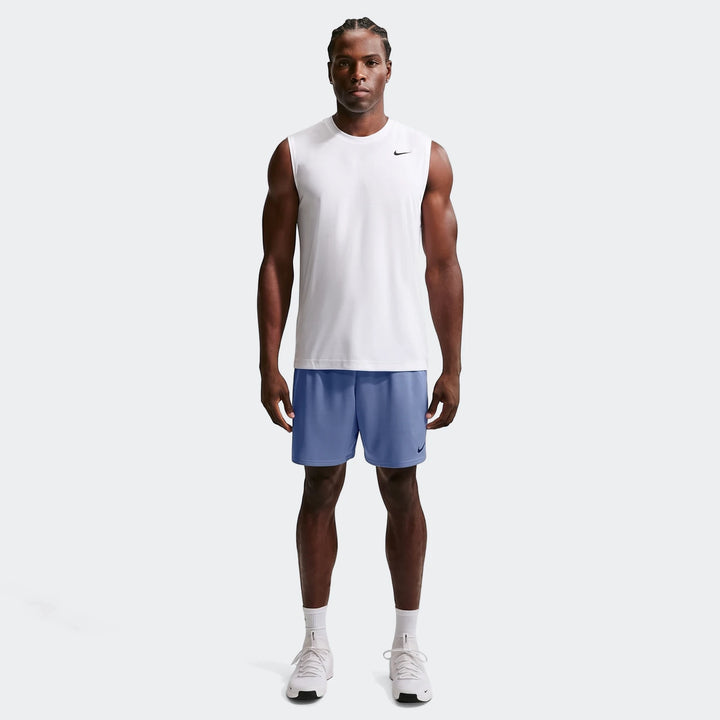 A man wearing blue Nike Flex Men's Dri-Fit 7" training shorts and a white sleeveless top, standing on a white background.