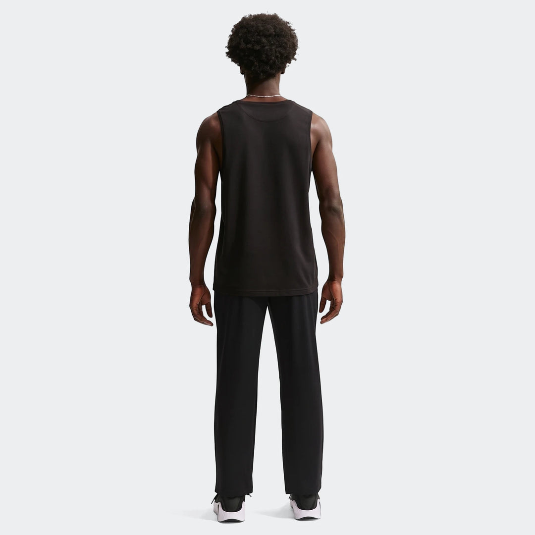 Full body back view of a man wearing black Nike Flex Men's Dri-Fit Pants and a black tank top on a white background.