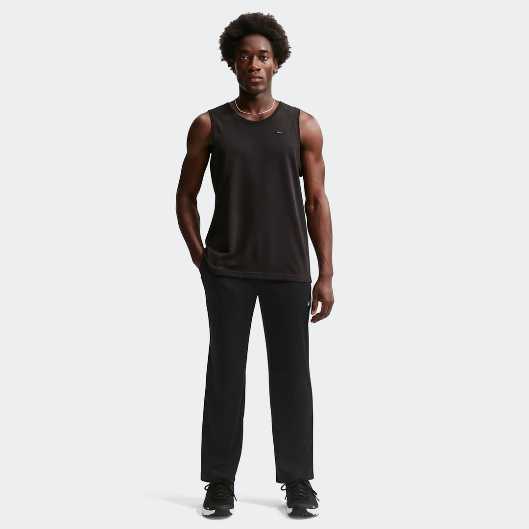 Man in black Nike Flex Dri-Fit pants and a black sleeveless shirt, standing on a white background.