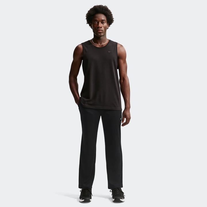Man in black Nike Flex Dri-Fit pants and a black sleeveless shirt, standing on a white background.
