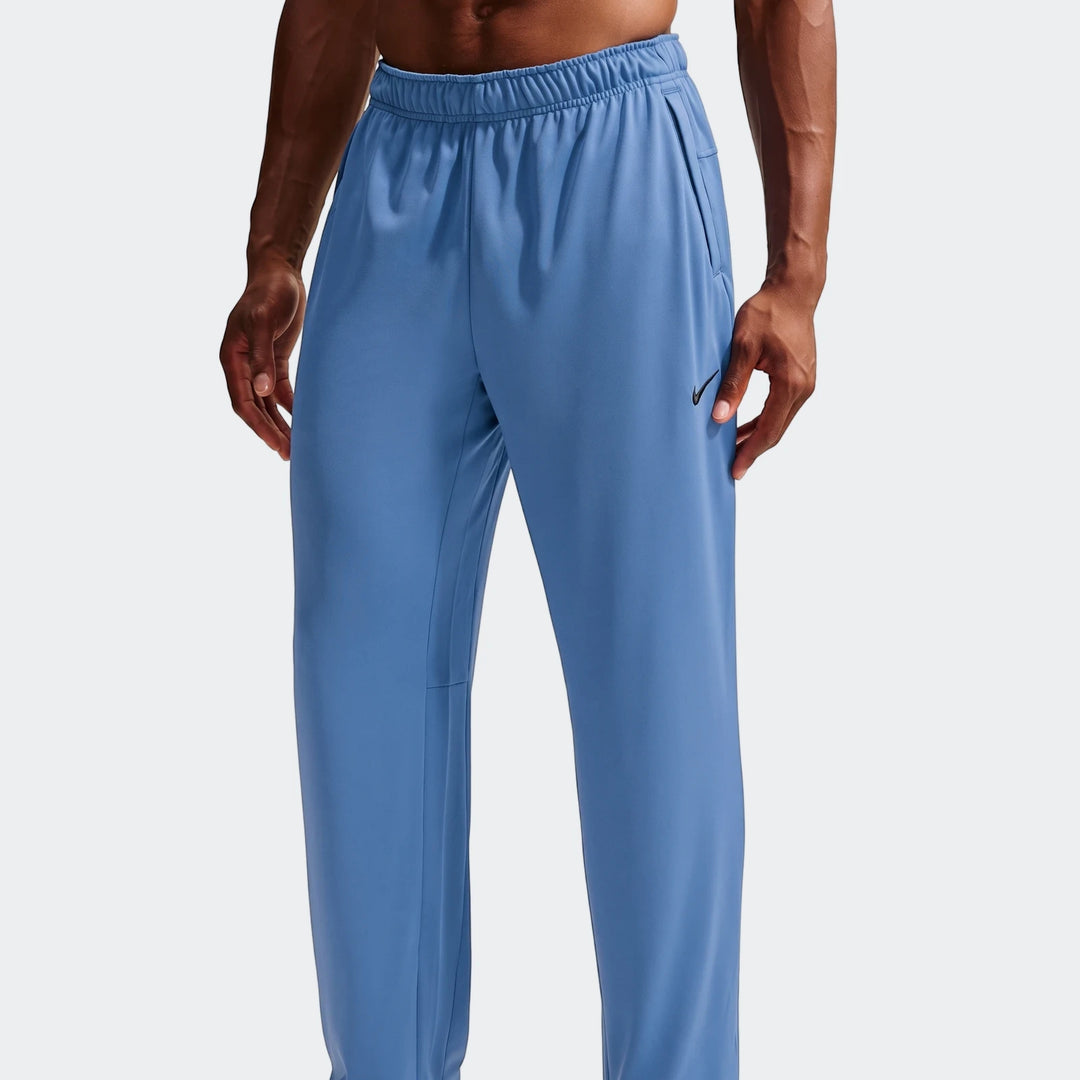 A man models blue Nike Flex Men's Dri-Fit pants, featuring an elastic waistband and the iconic swoosh logo.