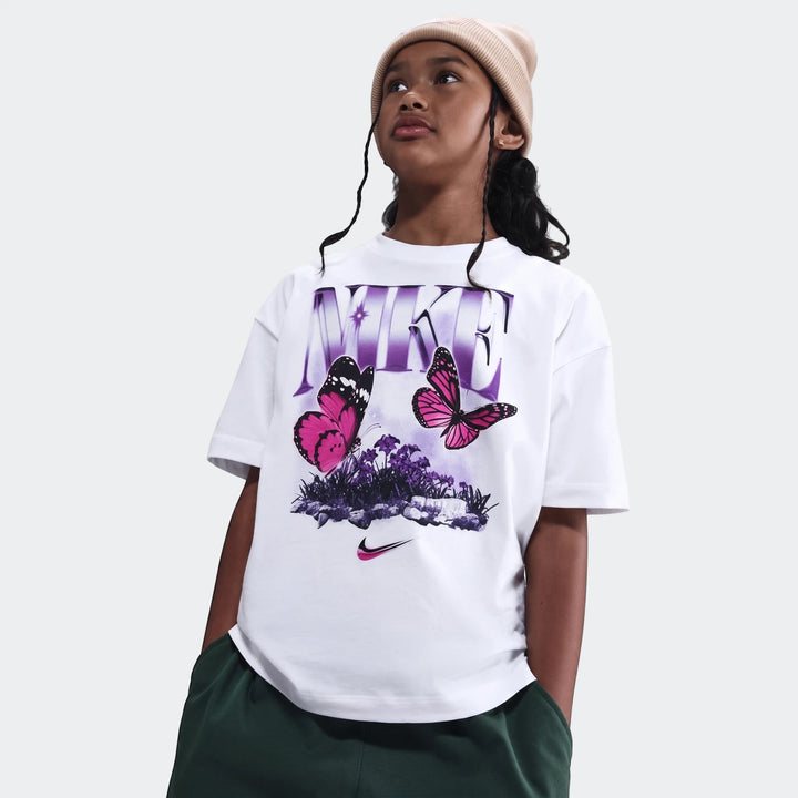 White Nike G Nsw Tee Butterfly oversized t-shirt with purple logo and pink butterflies, worn by a child with a beige beanie.