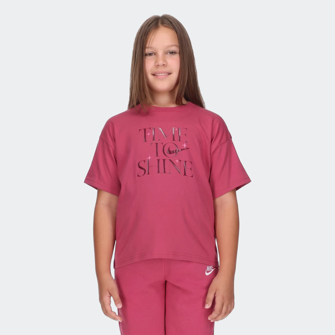 Young girl wearing a red Nike 'Time to Shine' t-shirt and matching sweatpants, smiling brightly.