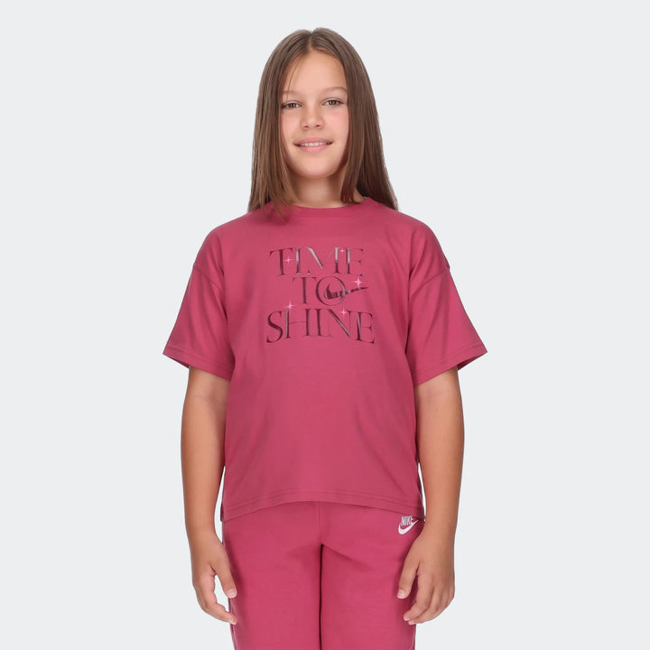 Young girl wearing a red Nike 'Time to Shine' t-shirt and matching sweatpants, smiling brightly.